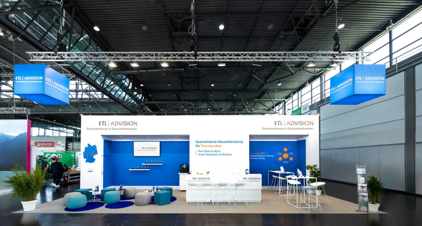 Messestand ETL Advision auf der therapie 2025 in Leipzig, Gesamtansicht mit Leuchtwürfeln und Lounge, geplant und gebaut von Marten Messe Management