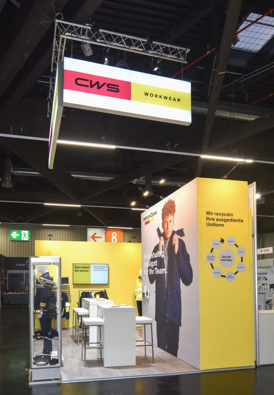 Der aufgebaute Messestand von CWS Workwear auf der Enforce Tac 2026 in Nürnberg mit beleuchtetem Logo in der Abhängung